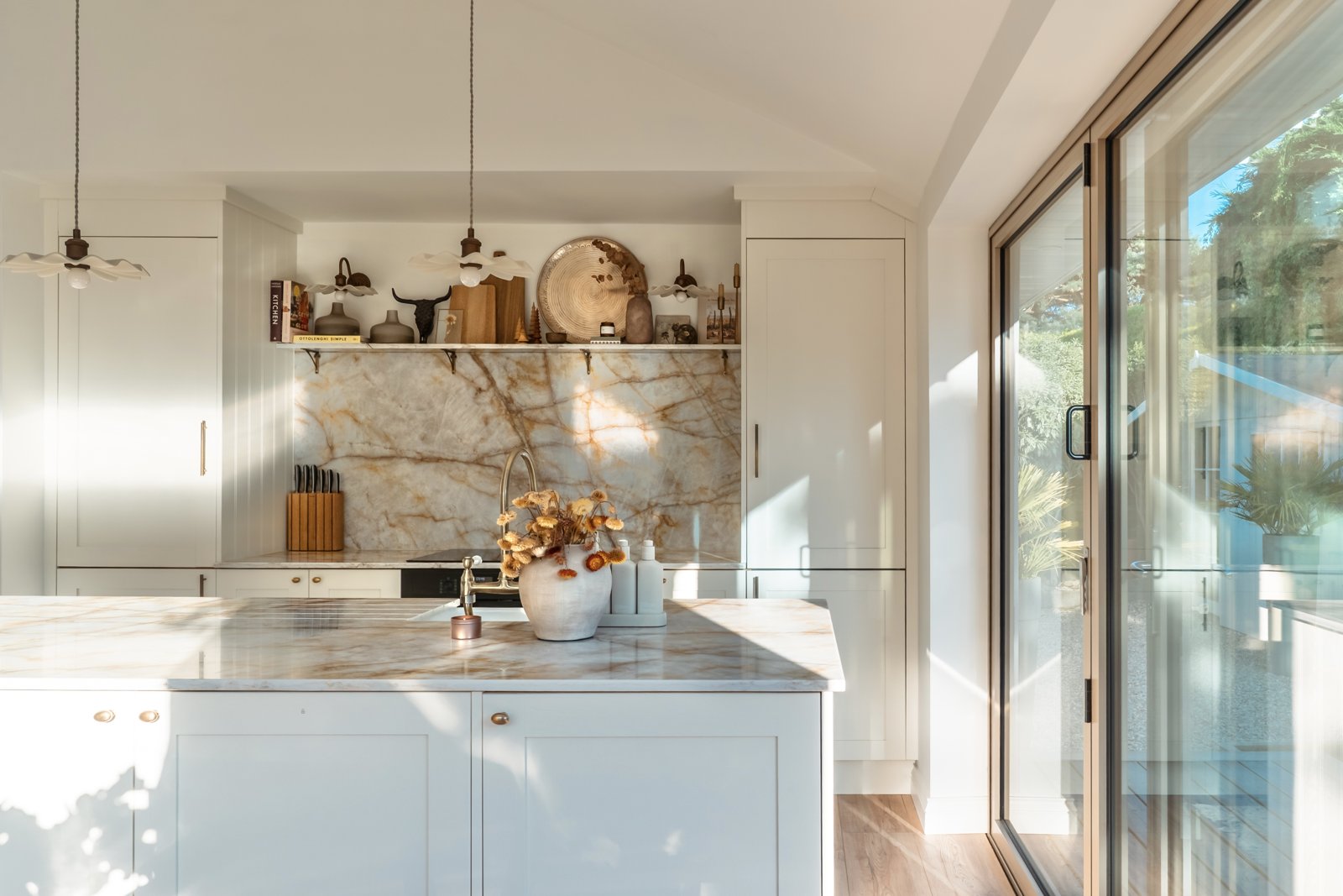 Sunlit kitchen with a marble island and garden-facing glass doors