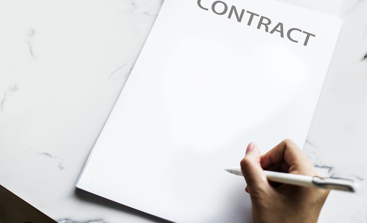 Hand holding a pen over a blank contract