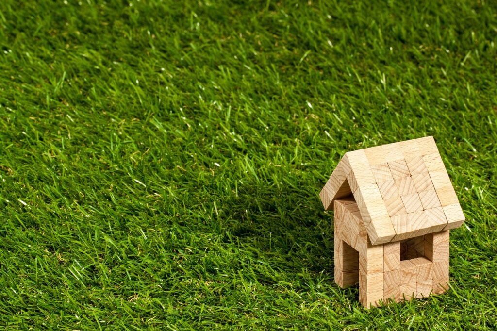 Small wooden house model on green grass